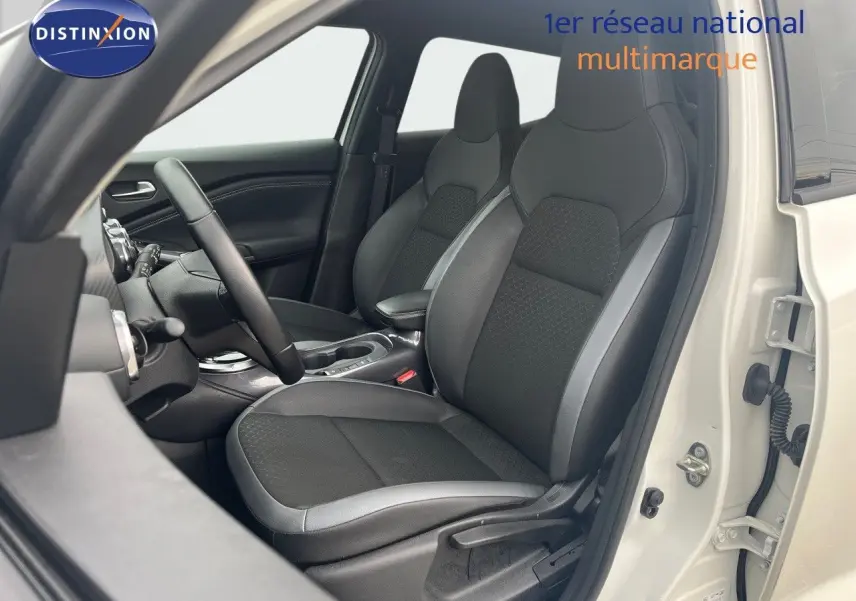 Vue intérieure côté gauche du Nissan Juke blanc nacré 2024, mettant en valeur les sièges avant en cuir noir et tissu.