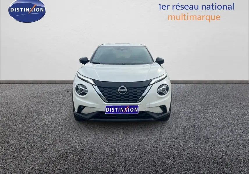 Vue frontale d'un Nissan Juke blanc nacré métal 2024 avec calandre noire et phares ronds LED.
