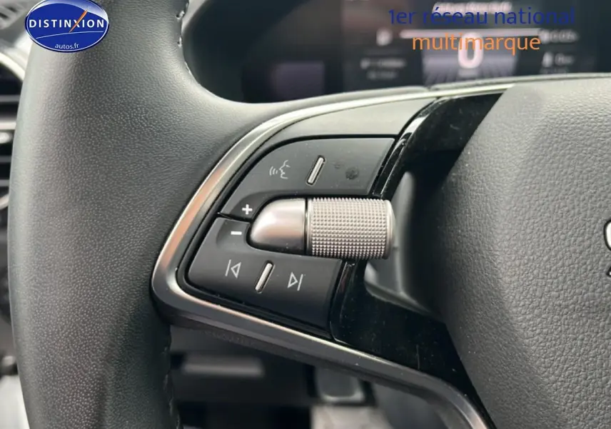 Gros plan sur les commandes gauche du volant cuir multifonction de la Skoda Fabia blanche 2025, avec molette argentée.