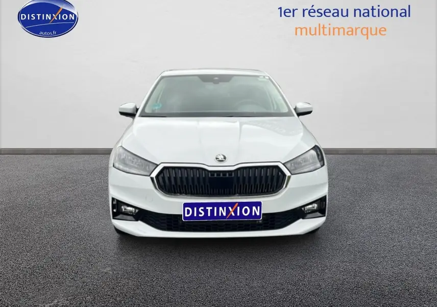 Vue de face d'une Skoda Fabia blanche 2025 avec calandre noire et phares LED, sur fond neutre intérieur showroom.