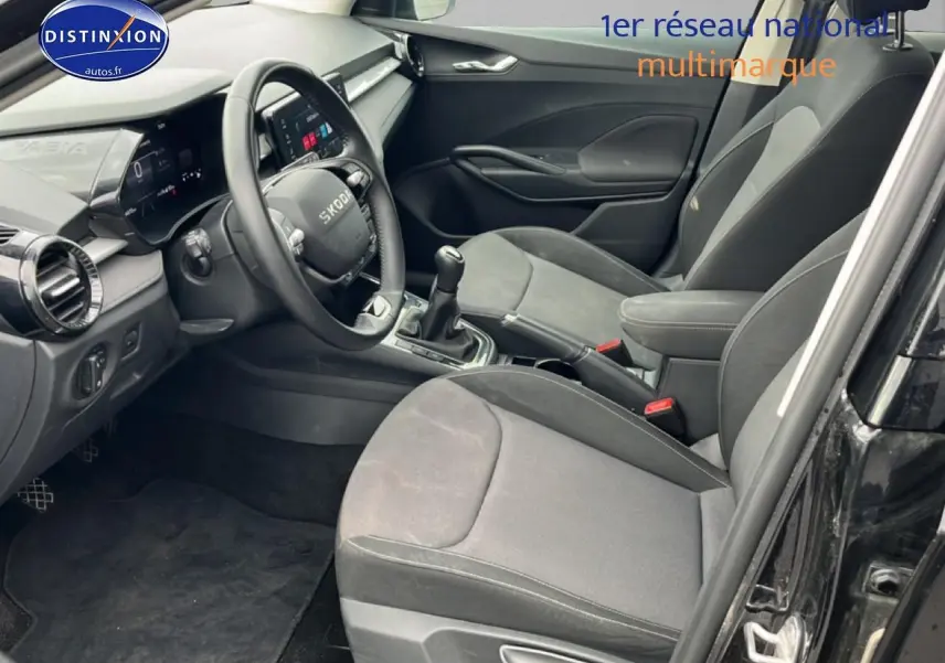 Intérieur avant droit d’une Skoda Fabia noire 2025, montrant sièges tissu gris et tableau de bord moderne.
