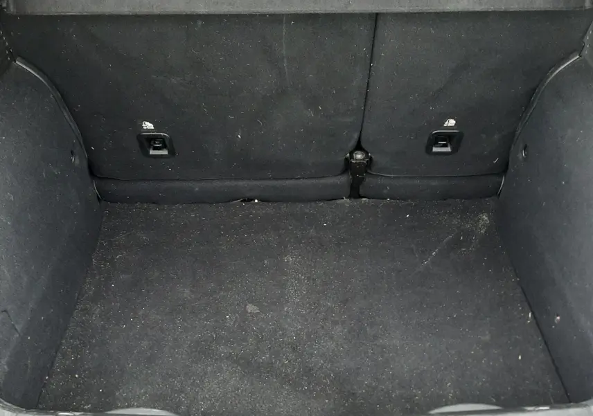 Coffre ouvert de FIAT 500X rouge 2016, montrant l'espace de chargement avec revêtement noir et sièges arrière rabattus.