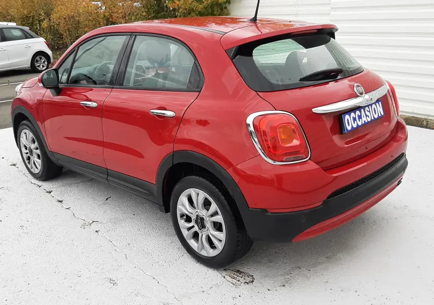 Vue 3/4 arrière droite d'une FIAT 500X rouge 5 portes avec jantes alliage et plaque "OCCASION" visible.