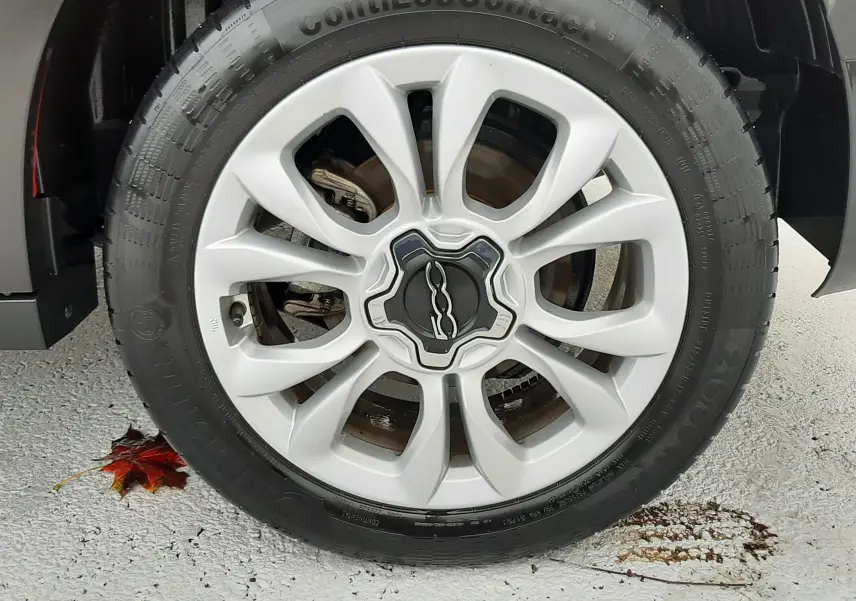 Gros plan sur la jante argentée avec logo FIAT 500 d'un FIAT 500X rouge, mettant en valeur le pneu ContiEcoContact.