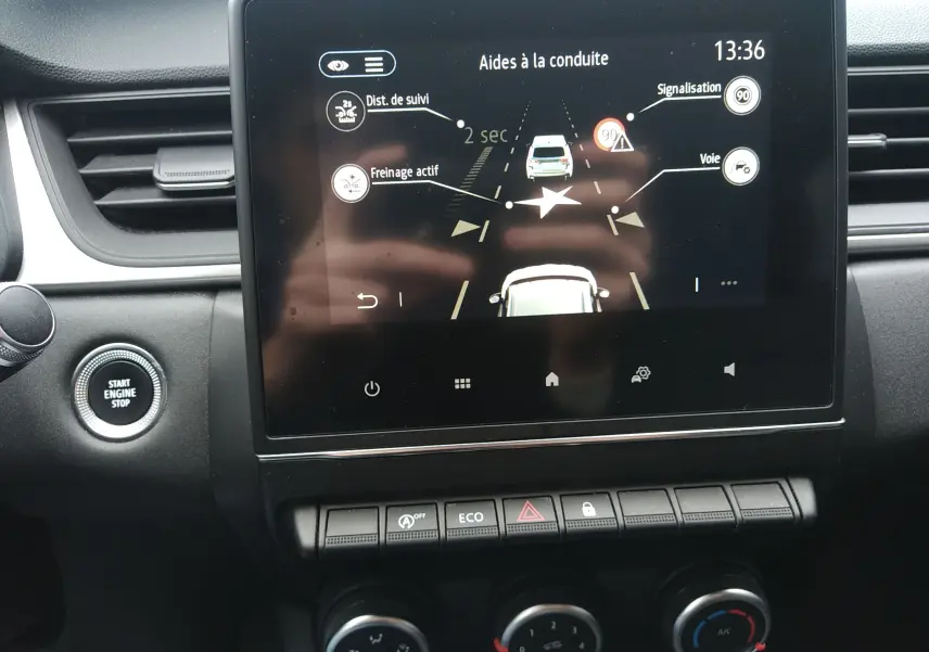 Vue rapprochée de l'écran tactile central du Renault Captur 2021 noir, affichant les aides à la conduite et boutons de commande.
