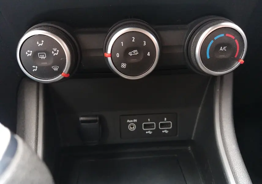 Gros plan sur les commandes de climatisation manuelle et les ports USB d'un Renault Captur noir, version Business 2021.