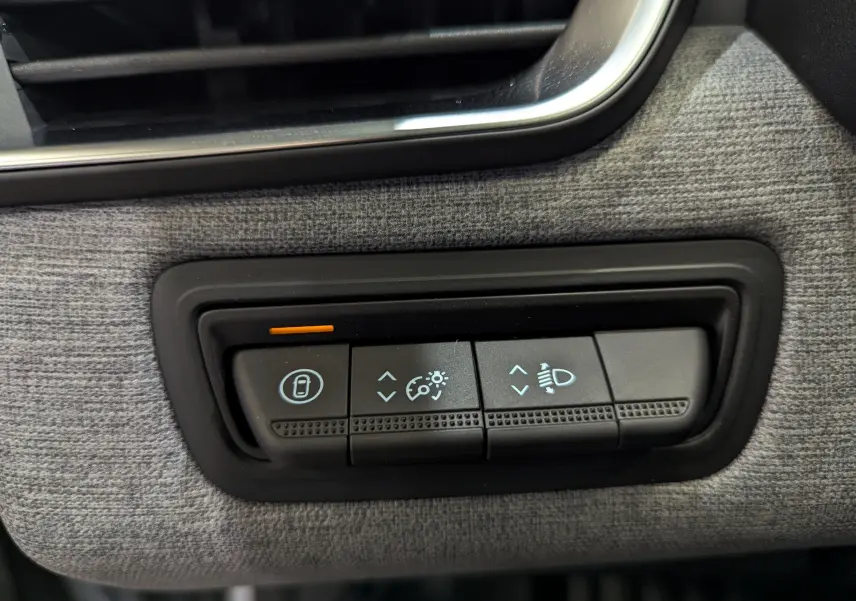 Gros plan sur les commandes d’éclairage et verrouillage intérieur de la planche de bord tissu gris d’une Renault Clio V Gris Rafale.