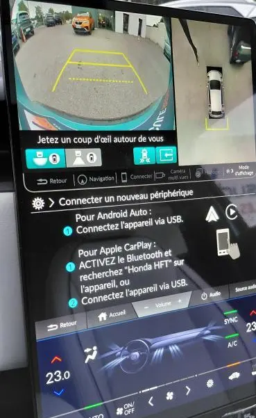 Écran intérieur de la Honda e:Ny1 204 ch Advance bleu montrant la caméra de recul et vue 360° en stationnement.