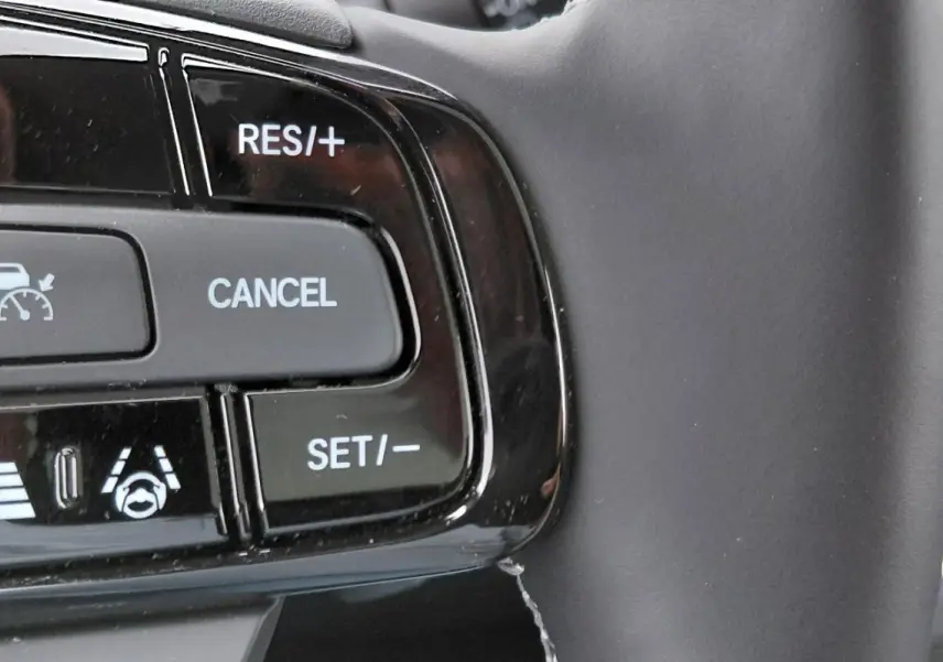 Gros plan sur les commandes de régulateur adaptatif au volant du Honda e:Ny1 Advance 2025, finition noire brillante.