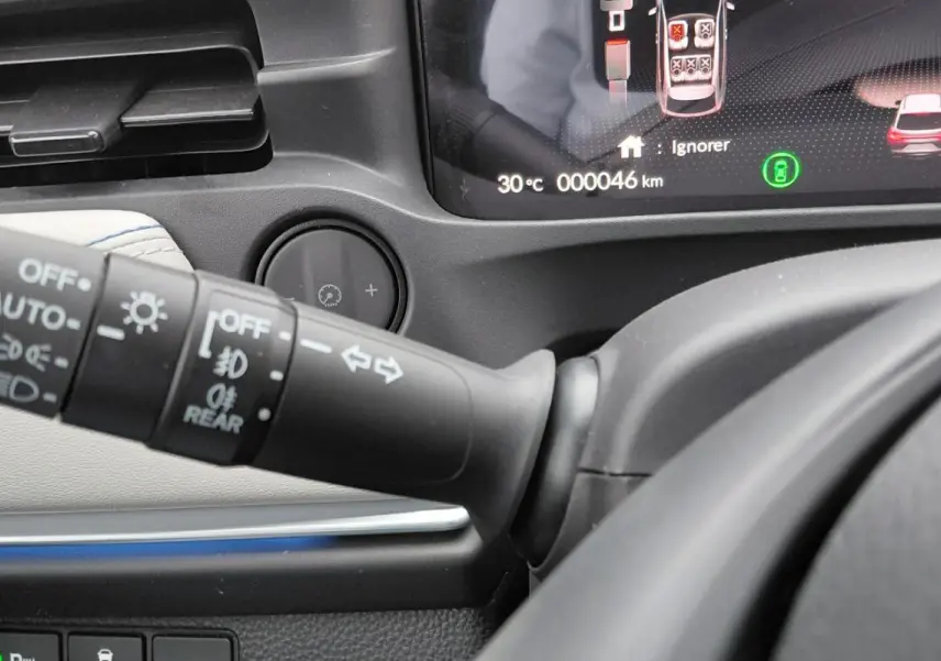 Gros plan sur la commande des feux et clignotants du Honda e:Ny1 204 ch Advance, avec tableau de bord numérique visible.