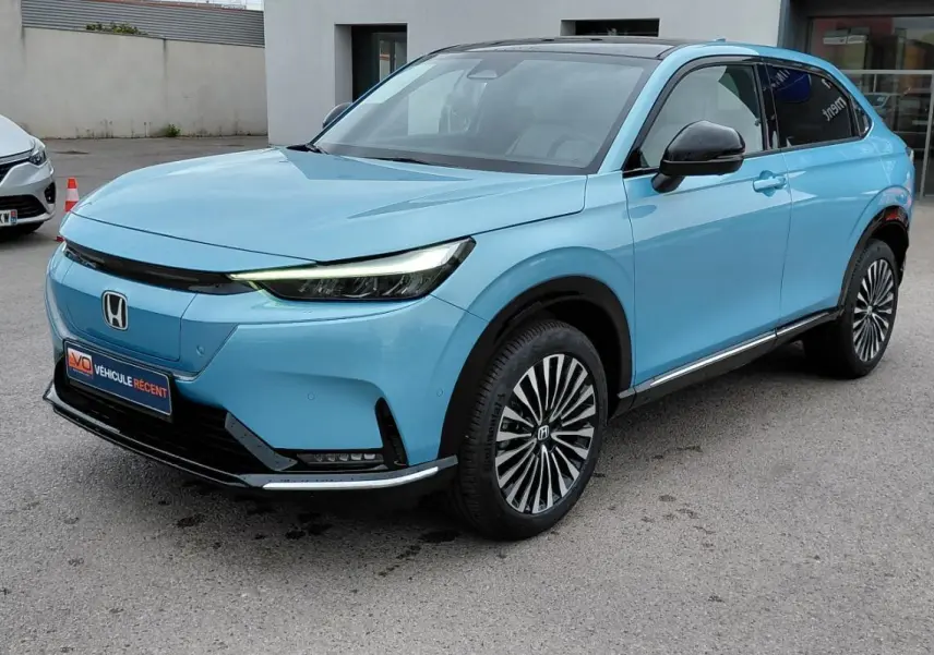 Vue 3/4 avant droite du Honda e:Ny1 Advance 204 ch bleu électrique avec jantes stylisées et toit noir.