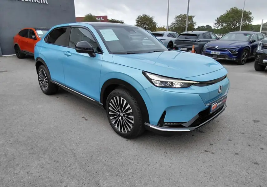 Honda e:Ny1 204 ch Advance bleu électrique vu en 3/4 avant droit, avec calandre épurée et jantes stylées.