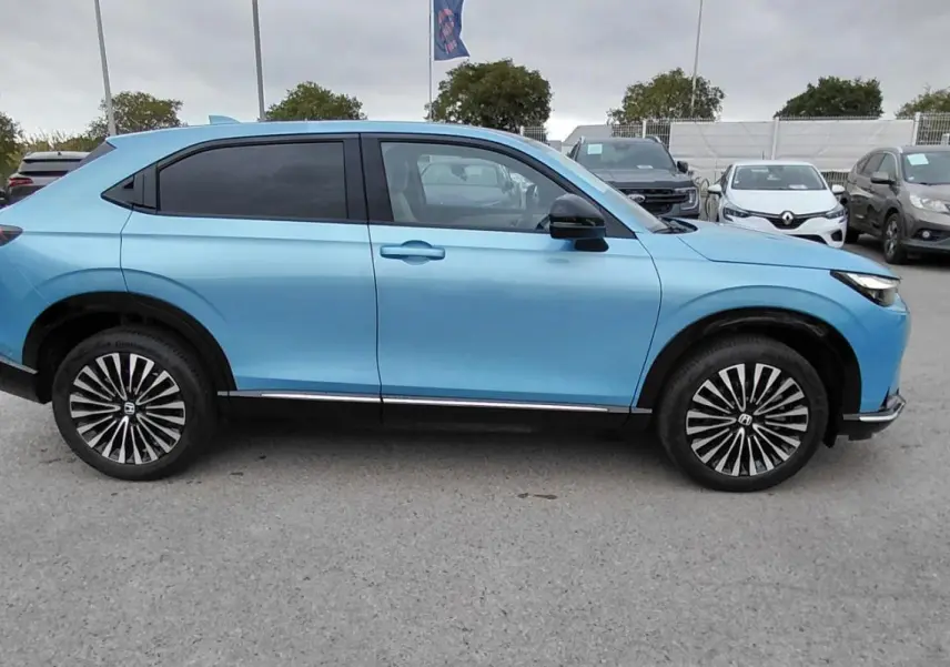 Vue de profil côté gauche d'un Honda e:Ny1 204 ch Advance 2025 bleu électrique avec jantes distinctives.