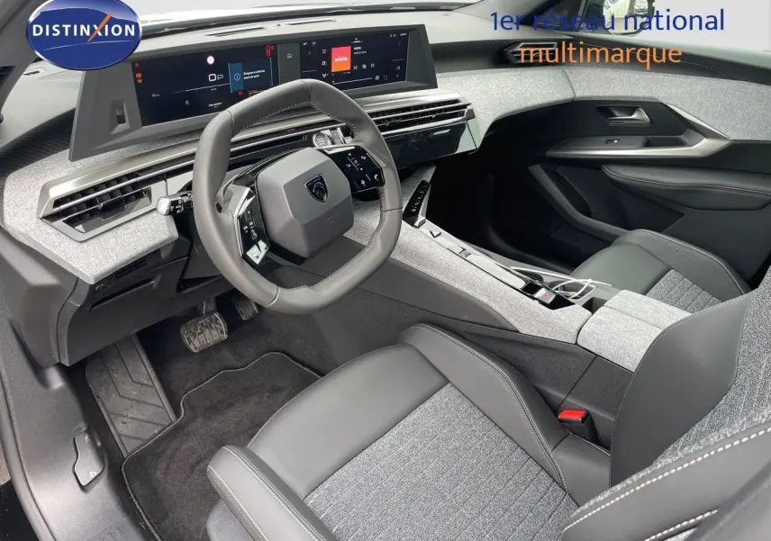 Intérieur du Peugeot 3008 Hybrid 2025 vu côté conducteur, avec tableau de bord numérique et sièges gris et cuir noir.