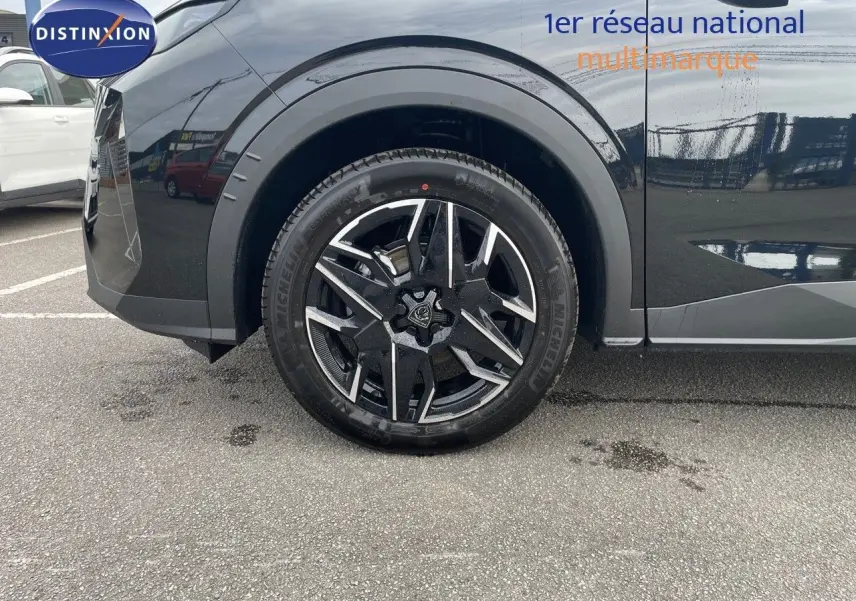 Gros plan sur la roue avant gauche du Peugeot 3008 noir perle métal, mettant en valeur la jante alliage bicolore.