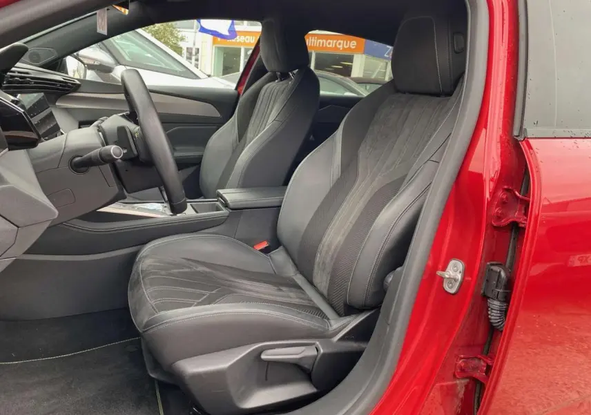 Intérieur côté conducteur de la Peugeot 308 rouge Elixir 2022, sièges sport en cuir et alcantara avec surpiqûres grises.