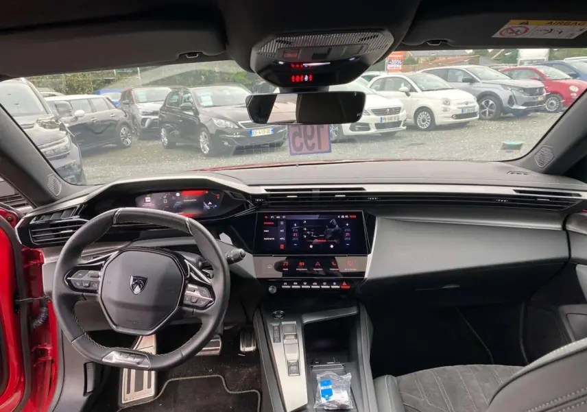 Vue intérieure avant de la Peugeot 308 rouge Elixir 2022, avec tableau de bord numérique et écran tactile central.