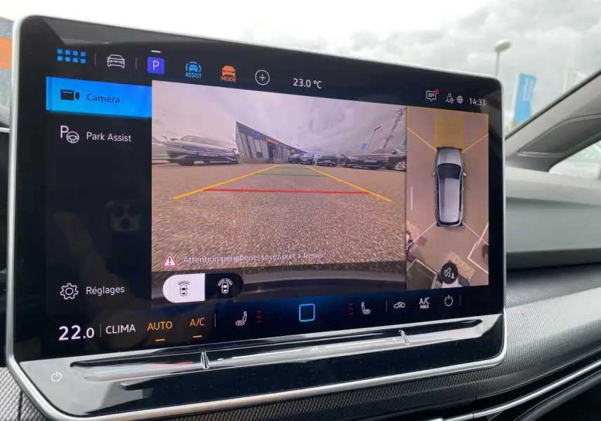 Écran tactile intérieur montrant la caméra 360° et l'aide au stationnement de la Volkswagen Golf 1.5 eTSI blanc nacré.