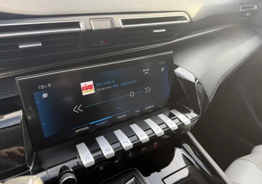 Vue rapprochée de la console centrale intérieure de la Peugeot 508 bleue, avec écran tactile et commandes piano chromées.
