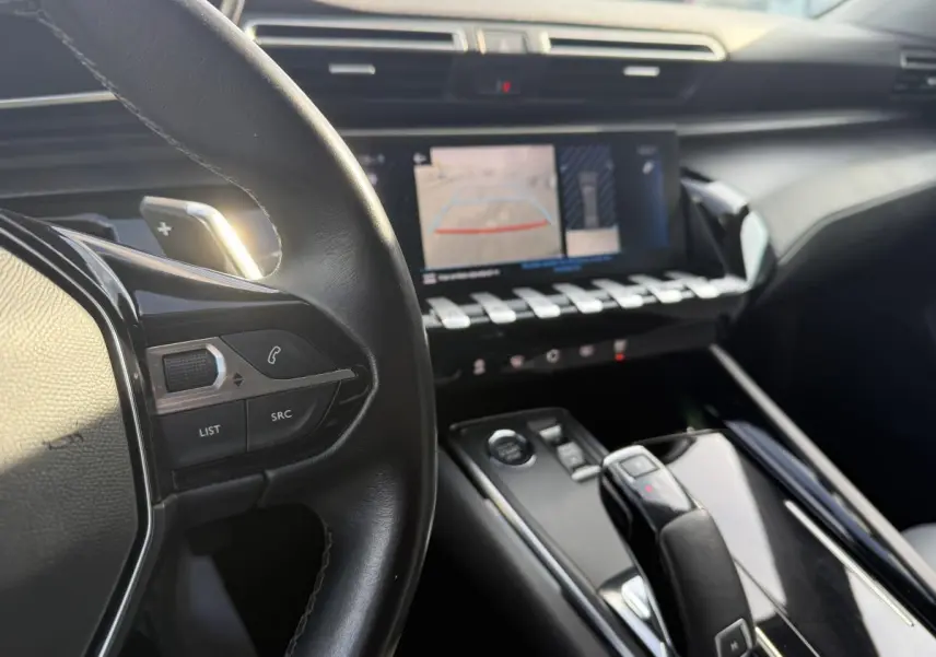 Vue intérieure centrée sur le volant cuir et la console centrale avec écran tactile et commandes chromées Peugeot 508 bleu.