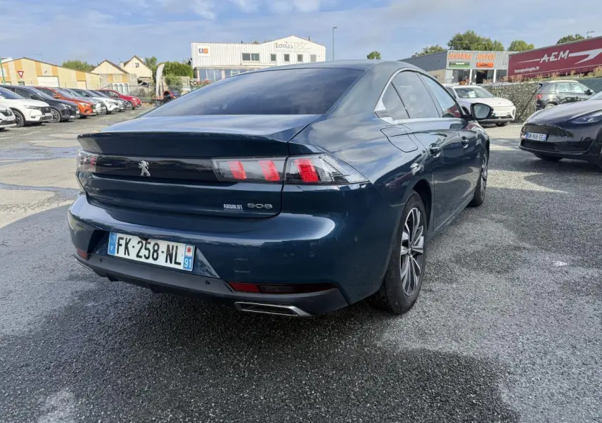 Vue 3/4 arrière droite d'une Peugeot 508 bleu métallisé avec feux arrière LED et double sortie d'échappement chromée.