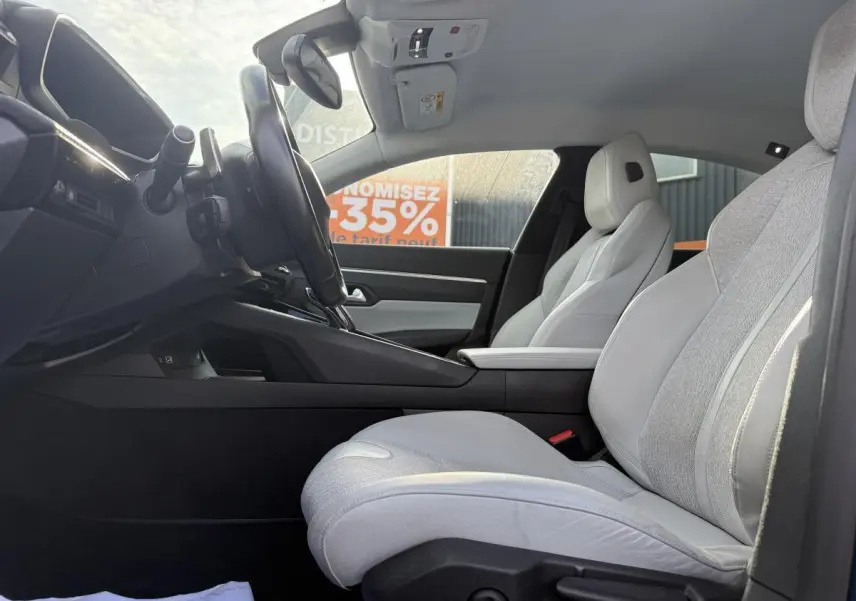Vue latérale intérieure côté conducteur de la Peugeot 508 2019 avec sièges tissu gris clair et console centrale noire.
