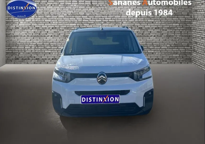 Vue frontale d'un Citroën Berlingo blanc 2025 avec logo chromé et pare-chocs noir dans un décor brique.