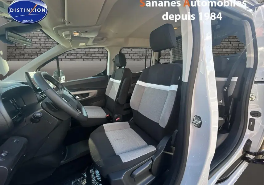 Vue intérieure côté gauche du Citroën Berlingo blanc 2025 montrant les sièges avant gris et noirs et le tableau de bord.