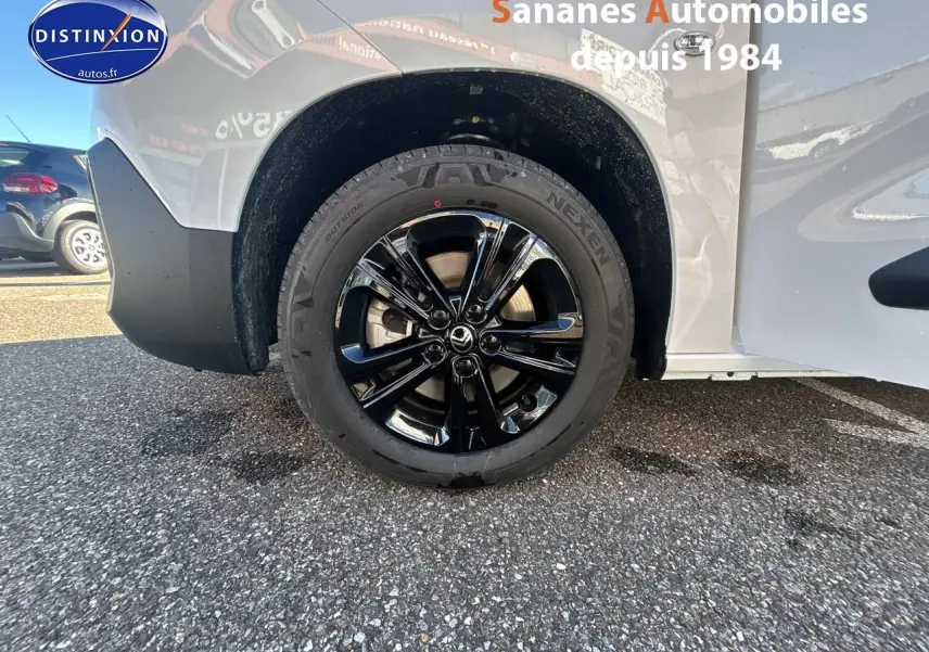 Gros plan sur la roue arrière droite noire brillante du Citroën Berlingo blanc, avec partie de la carrosserie visible.