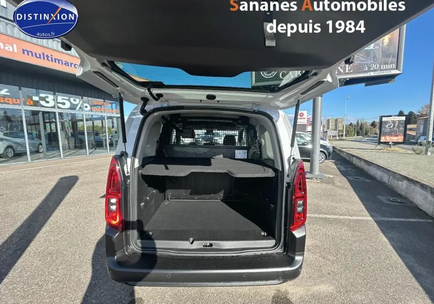 Vue arrière ouverte du Citroën Berlingo blanc montrant le coffre spacieux et la grille de séparation intérieure.