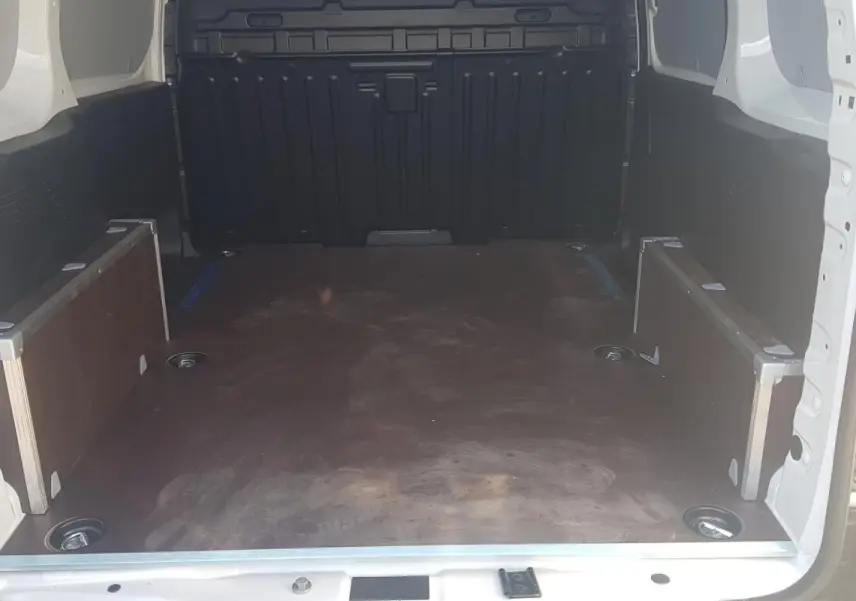 Vue intérieure arrière du Citroën Berlingo blanc 2025, montrant l'espace de chargement vide avec plancher en bois.