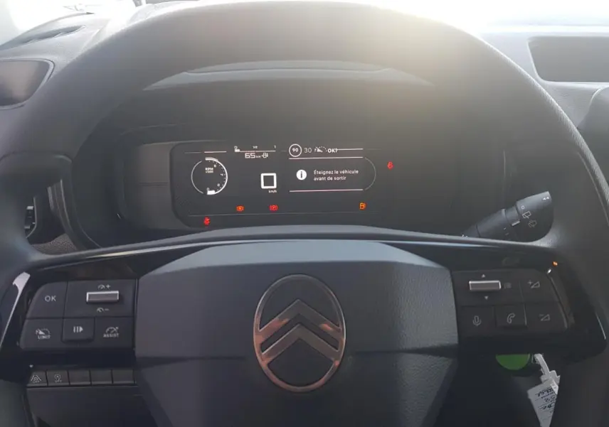 Vue rapprochée du volant multifonctions noir et du tableau de bord numérique du Citroën Berlingo blanc 2025.