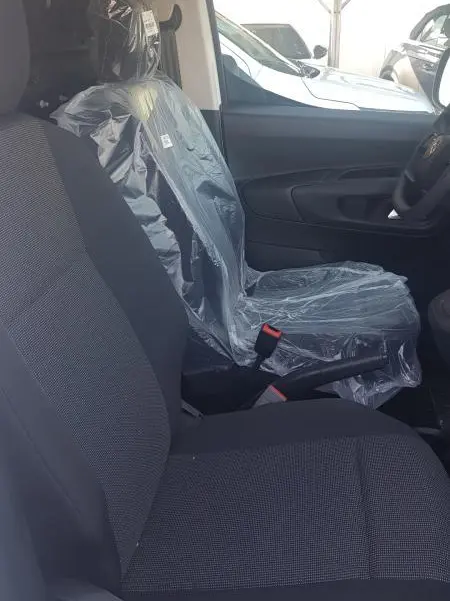 Vue intérieure côté droit du siège avant passager du Citroën Berlingo blanc 2025, siège protégé par housse plastique.