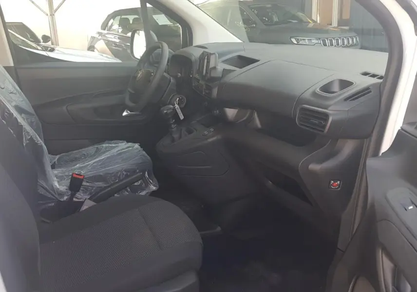 Vue intérieure côté conducteur du Citroën Berlingo blanc 2025, montrant le tableau de bord et la sellerie noire.
