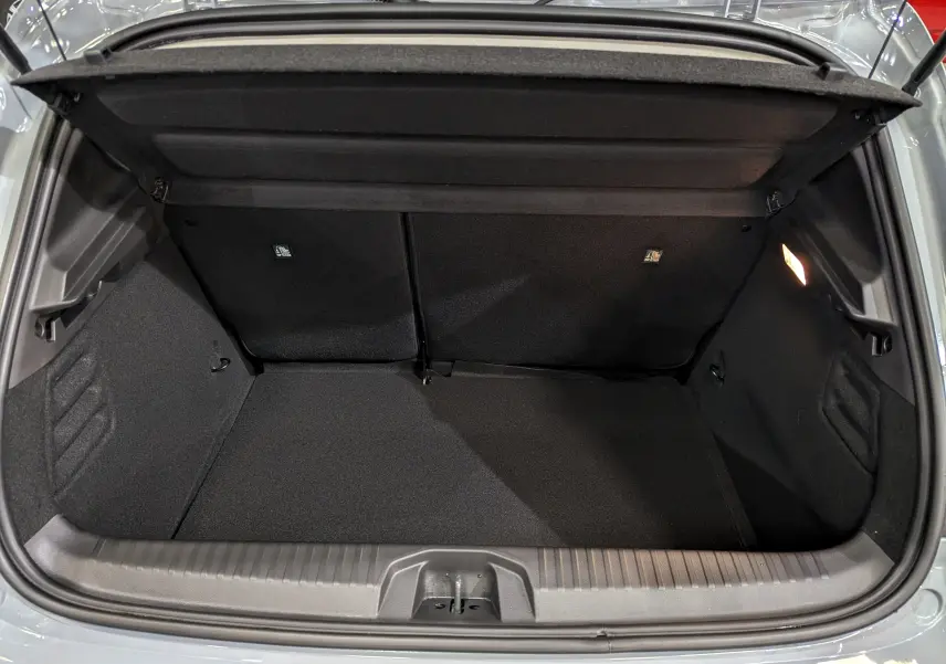 Coffre ouvert vu de face d'une Renault Clio V gris Rafale, montrant l'espace de rangement intérieur propre et éclairé.