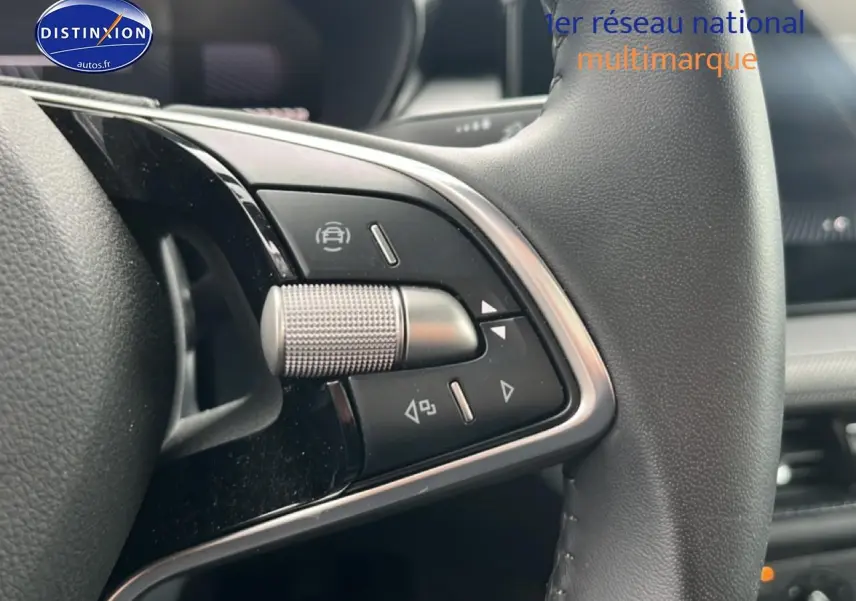 Gros plan sur les commandes multifonctions en aluminium et cuir du volant de la Skoda Fabia blanche 2025.