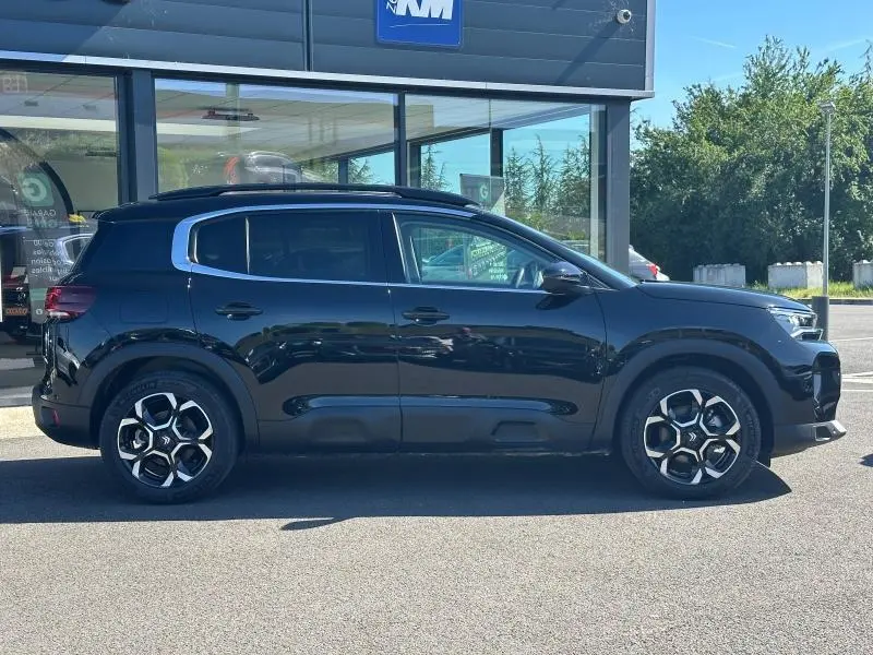 Profil droit du Citroën C5 Aircross 2025 noir Perla Nera avec jantes distinctives et barres de toit visibles.