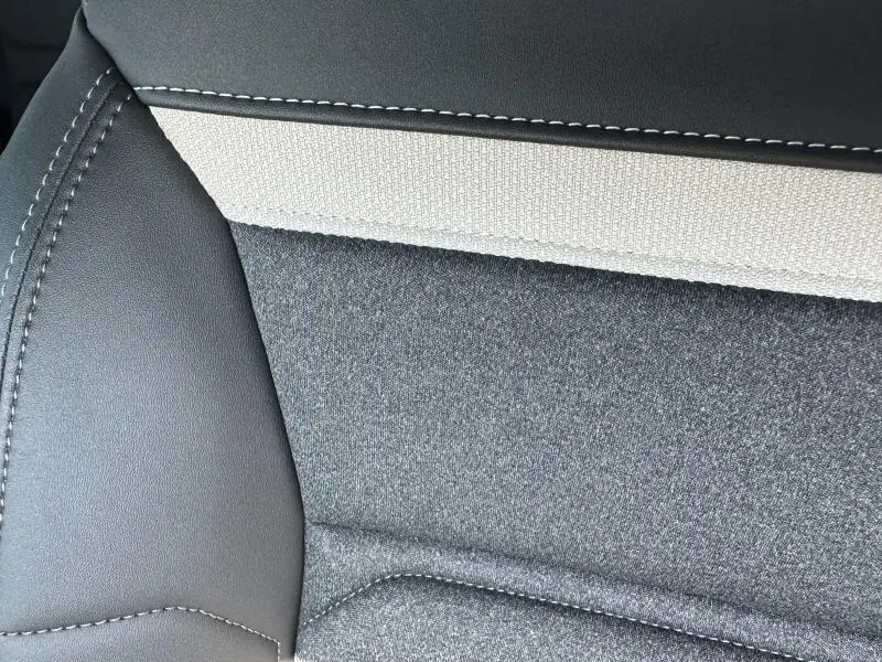 Détail du revêtement de siège en tissu gris et cuir noir avec surpiqûres blanches dans un Citroën C5 Aircross 2025.