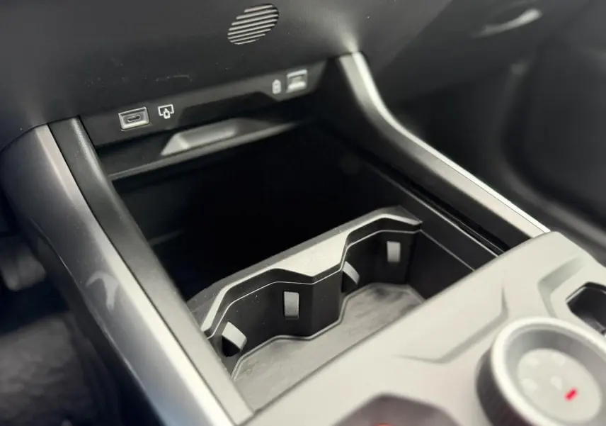 Gros plan sur la console centrale noire du Jeep Compass Hybrid 2026, avec porte-gobelets et ports USB visibles.