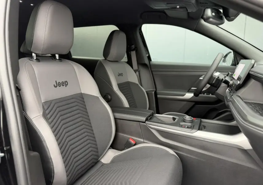 Vue intérieure côté droit du Jeep Compass 2026, sièges gris avec logo Jeep et console centrale moderne.