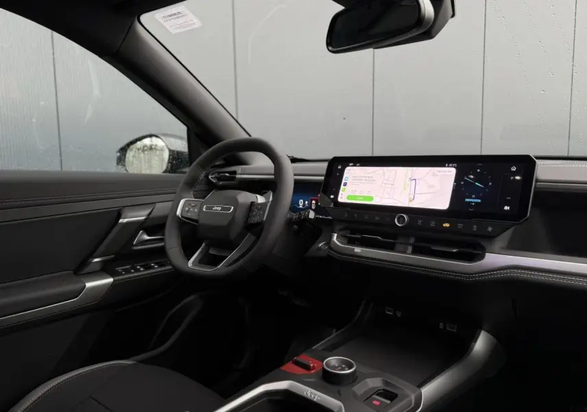 Intérieur noir du Jeep Compass Hybrid 2026 vu côté conducteur, avec grand écran tactile et volant multifonction.