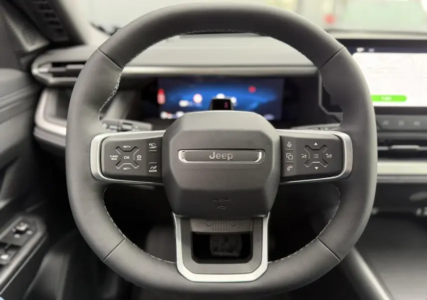 Vue frontale centrée sur le volant noir du Jeep Compass 2026 avec commandes intégrées et tableau de bord numérique.