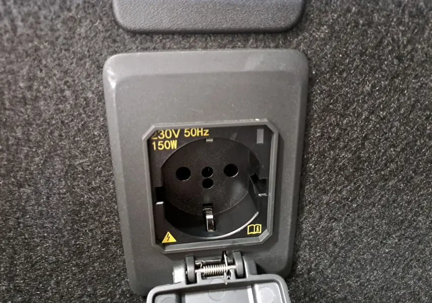 Prise électrique 230V 150W intégrée dans le coffre du CUPRA LEON ST 1.5 eTSI 2025, finition Noir Minuit.