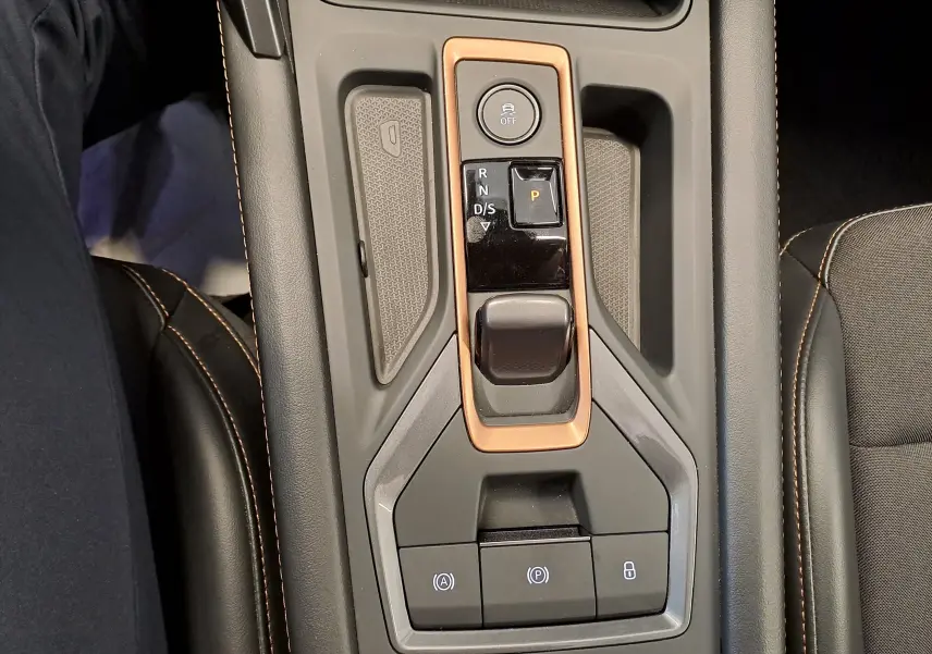 Gros plan sur la console centrale de la CUPRA LEON ST 1.5 eTSI 150 DSG7 avec cadre cuivré et boutons de commande.