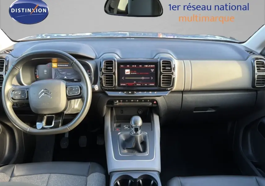 Vue intérieure frontale du tableau de bord et volant du Citroën C5 Aircross gris avec boîte manuelle et écran tactile central.