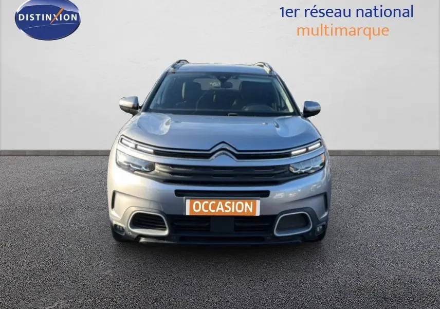 Vue frontale d'un Citroën C5 Aircross gris Artense métal avec calandre distinctive et phares LED allumés.