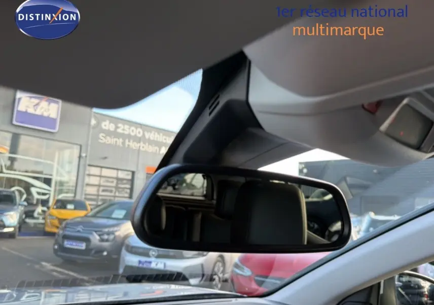 Vue intérieure centrée sur le rétroviseur intérieur d’un Citroën C5 Aircross gris Artense, avec parking en arrière-plan.