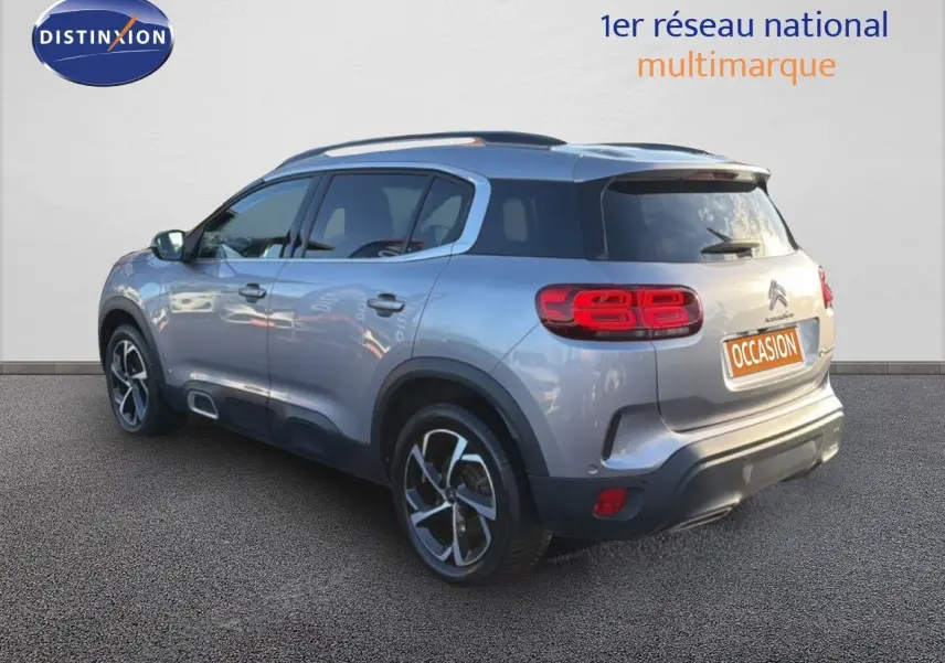 Vue 3/4 arrière droite d'un Citroën C5 Aircross gris Artense métallisé avec jantes bi-ton et feux LED distinctifs.