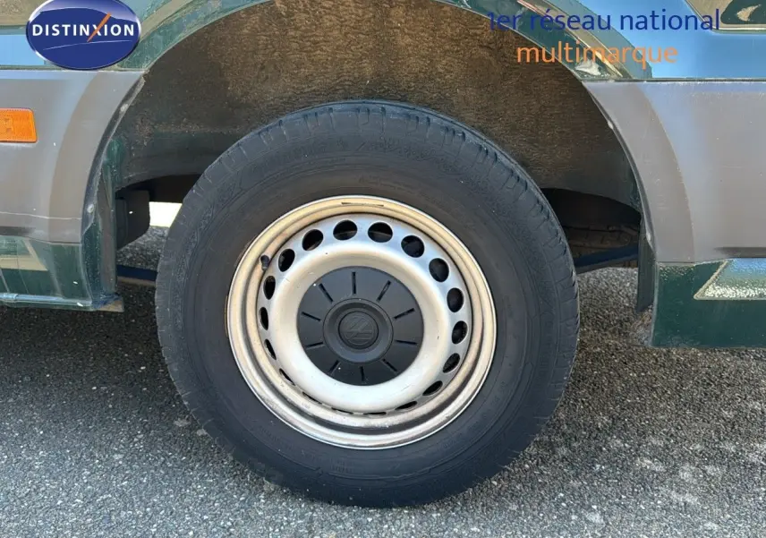 Gros plan sur la roue avant gauche du Volkswagen Crafter vert Ontario, soulignant la jante acier d'origine.