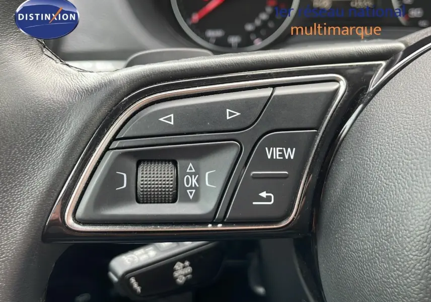 Gros plan sur les commandes multifonctions noires du volant d'un Audi Q2 noir mito metal 2023.